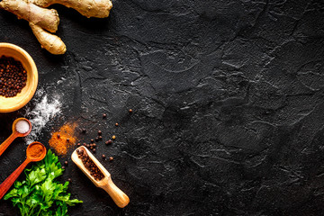 spices in wooden spoon on dark background top view