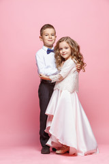 Fototapeta na wymiar Boy and girl standing in studio on pink background