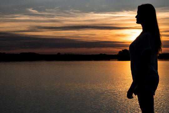 Colorful Sunset And Silhouette Of Woman On The Lake