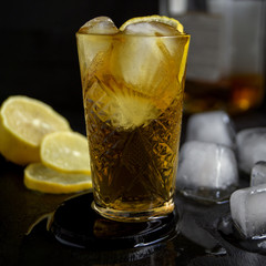 A glass of whiskey on the black table.