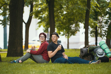 Young couple - man and woman - tourists with backpacks are eating the icecream in the park