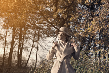 beautiful woman in a coat hat and a white dress for a walk in an autumn park or forest.