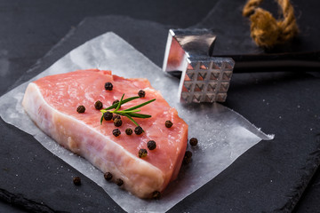 Meat, pork, slices pork loin with meat tenderizer on dark background