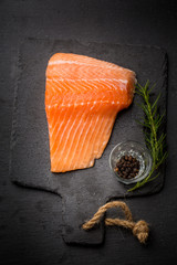 Raw salmon filet on dark slate background