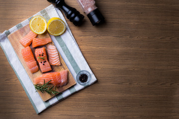 Fresh salmon fillet with aromatic herbs spices on wooden background.