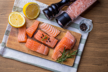 Fresh salmon fillet with aromatic herbs spices on wooden background.