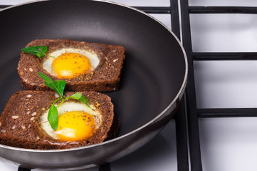 Breakfast -  toast with processed cheese tomato, fried eggs , fried eggs, teapot and cup of tea on a gray wood background.