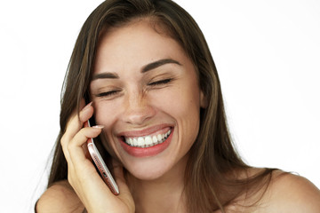 Fototapeta premium Pretty laughing woman talks on the phone standing on white background