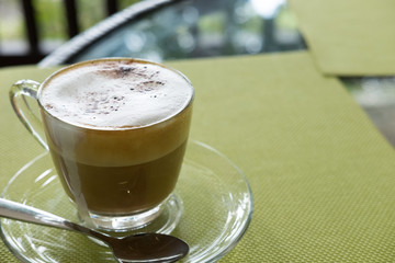 Cup of cappuccino coffee, hot mocha drink with cinnamon and cocoa powder in glass mug