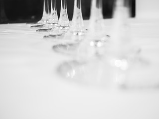 Closeup stem and foot of wine glasses on white cover table.