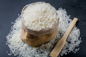 Raw grain white rice grains in sack with dark background