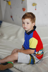 Cute little boy sitting deep in thought at the wall climbing
