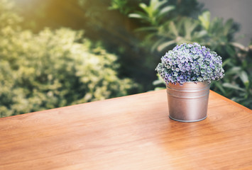 A small tree vase on a wooden table with a garden as the background blurred.