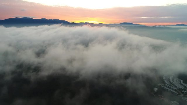Aerial view. Flying backwards as the clouds passes during beautiful sunrise.