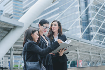 Asian business women holding document while standing outside discuss new project