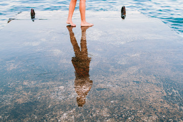 Female wet feet on the pier on the background of the sea © alexbutko_com