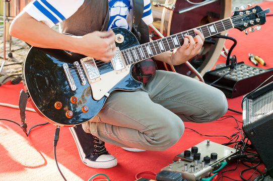 guitarist sets up an electric guitar before the concert begins on the street