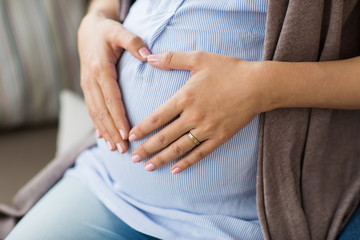 close up of pregnant woman making heart on belly