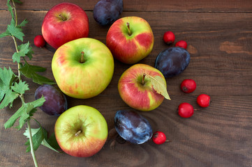 apples and plums on wooden table