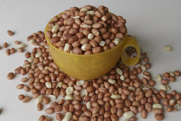 Vegan food. Raw Peanuts for roasting closeup. Yellow Cup on a white background.