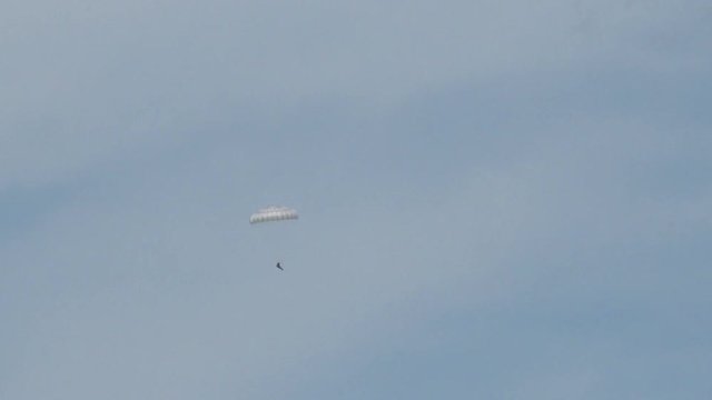 Paratroopers in the sky. White parachute on blue sky background .