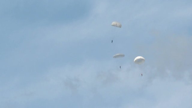 Paratroopers in the sky. White parachute on blue sky background .