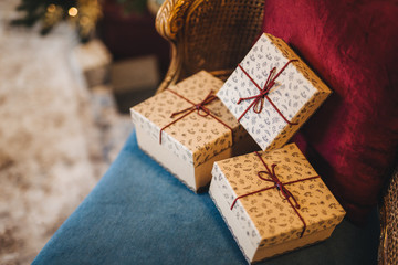 Holiday, celebration and surprise concept. Boxes of gifts lie on grand armchair, waits for host. Happy feeling to New Year. Gift box with ribbons on coach at home. Holiday concept.