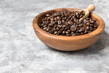 Coffee beans in a wooden bowl on a light marble background with copy space in a minimalist style