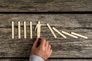 Man stopping the domino effect with a paper cutout silhouette