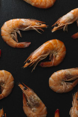 Shrimps on black background. Delicious seafood appetizer served boiled or grilled with spices. Close up. Top view