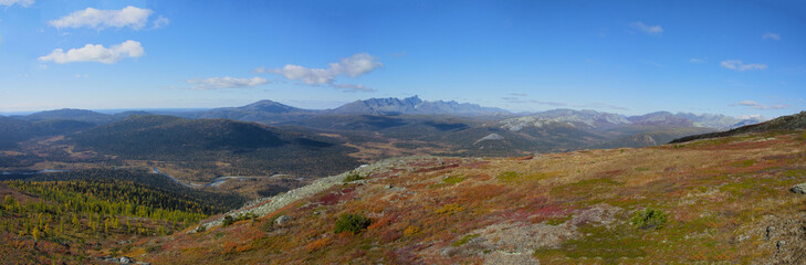 Ural autumn landscape - snow-capped peaks, mountain forests, yellow foliage, transparent cold rivers