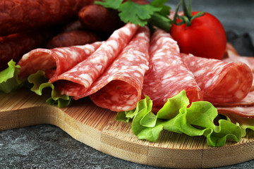 Food tray with delicious salami, pieces of sliced ham, sausage, tomatoes, salad and vegetable - Meat platter with selection - Cutting sausage and cured meat