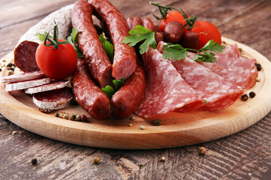 Food tray with delicious salami, pieces of sliced ham, sausage, tomatoes, salad and vegetable - Meat platter with selection - Cutting sausage and cured meat