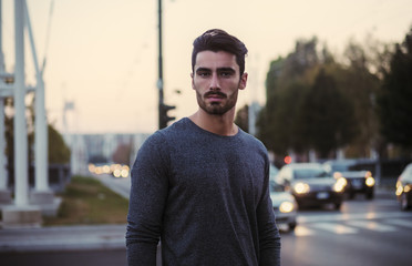 Attractive young man portrait at night with city lights behind him in Turin, Italy
