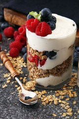 Glass jar of homemade granola with yogurt and fresh berries