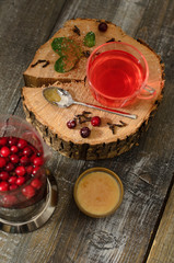 Hot drink of cranberries in а teapot and in a cup with honey on wooden background © AR-tem