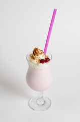 Milkshake with whipped cream and berries in a glass on white background