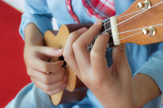 Teen girl playing ukulele. Closeup her hand. Acoustic music. Small string music instrument.