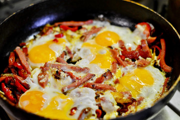 Shakshuka - fried eggs with tomatoes, onion, pepper and spices in iron pan, dark style