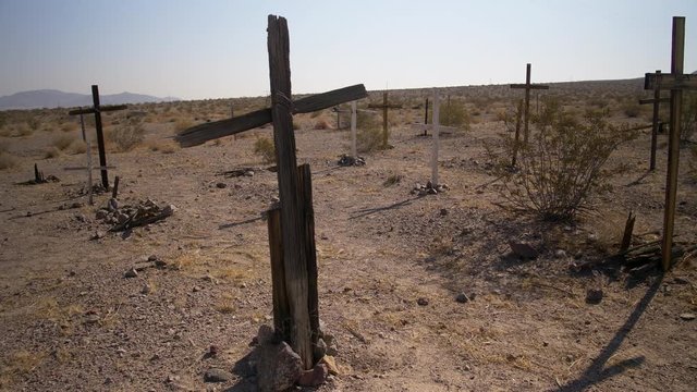 UNMARKED WOODEN CROSSES IN A DESERT CEMETERY, IN 4K.  Slow, wide dolly shot of a desert cemetery.  Shot in 4K, 10 bit, 4:2:2.