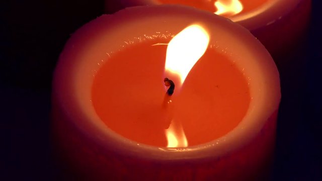 Red candles burn against a black background. The fire the flame of a candle. Enchanting view of flames. Candles - a symbol of memory.