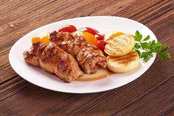 Grilled meat rolls with vegetables on wooden background