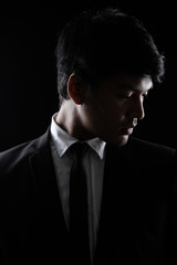 Asian man in black fomal suit in the dark