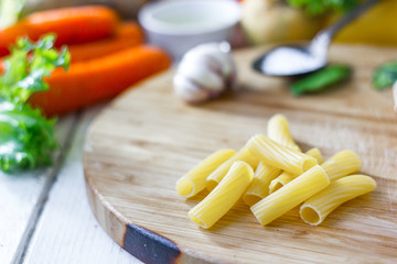Italian pasta rigatoni over the wooden board.