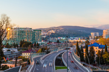 Aerial view of city, mountains and highway "Doubler of Kurortnyy Prospekt" at sunset, Sochi, Russia