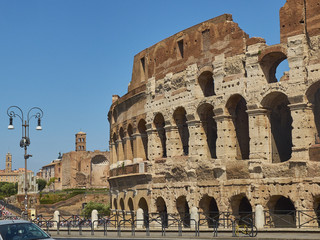 Fototapeta premium The roman Colosseum (also known as Flavian Amphitheatre) with the Temple of Venus and Rome and Santa Francesca Romana bell tower in background. View from Via Celio Vibenna. Rome, Lazio, Italy.