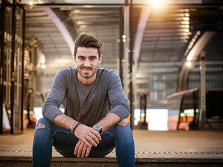 Attractive young man portrait at night with city lights behind him in Turin, Italy