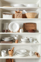 Fototapeta na wymiar Storage stand with tableware and kitchen utensils indoors