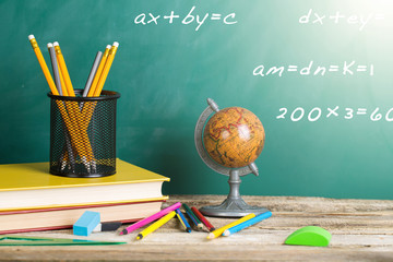Back to school supplies. Books and blackboard on wooden background