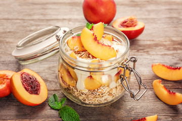 Jar with oat flakes and fresh peaches on wooden background